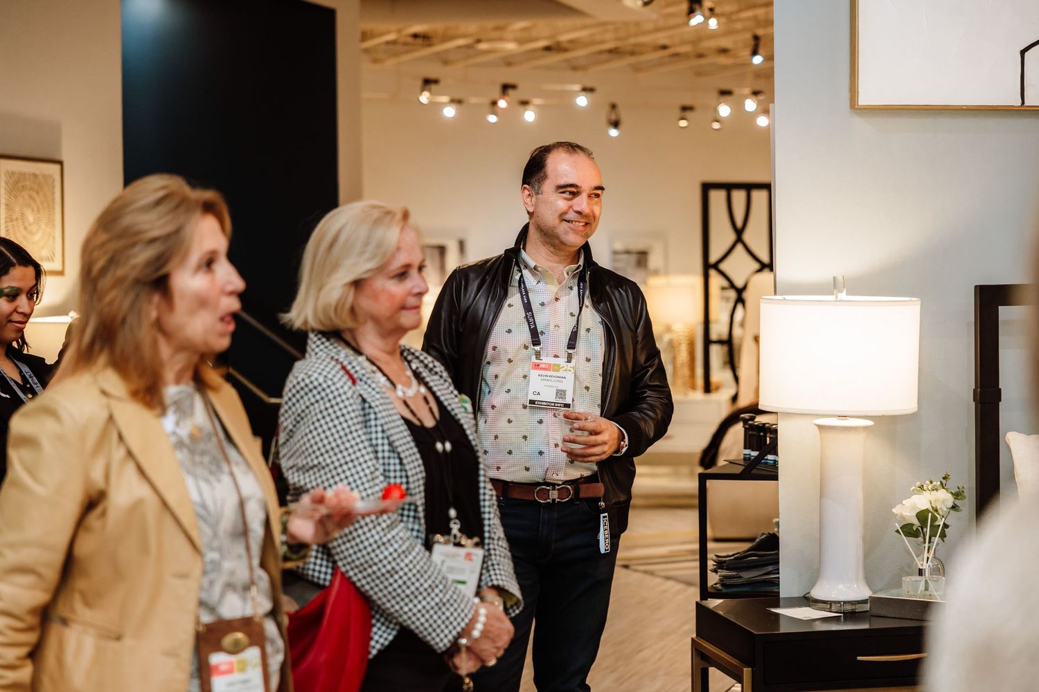 Attendees browsing furniture showroom at an interior design trade event.