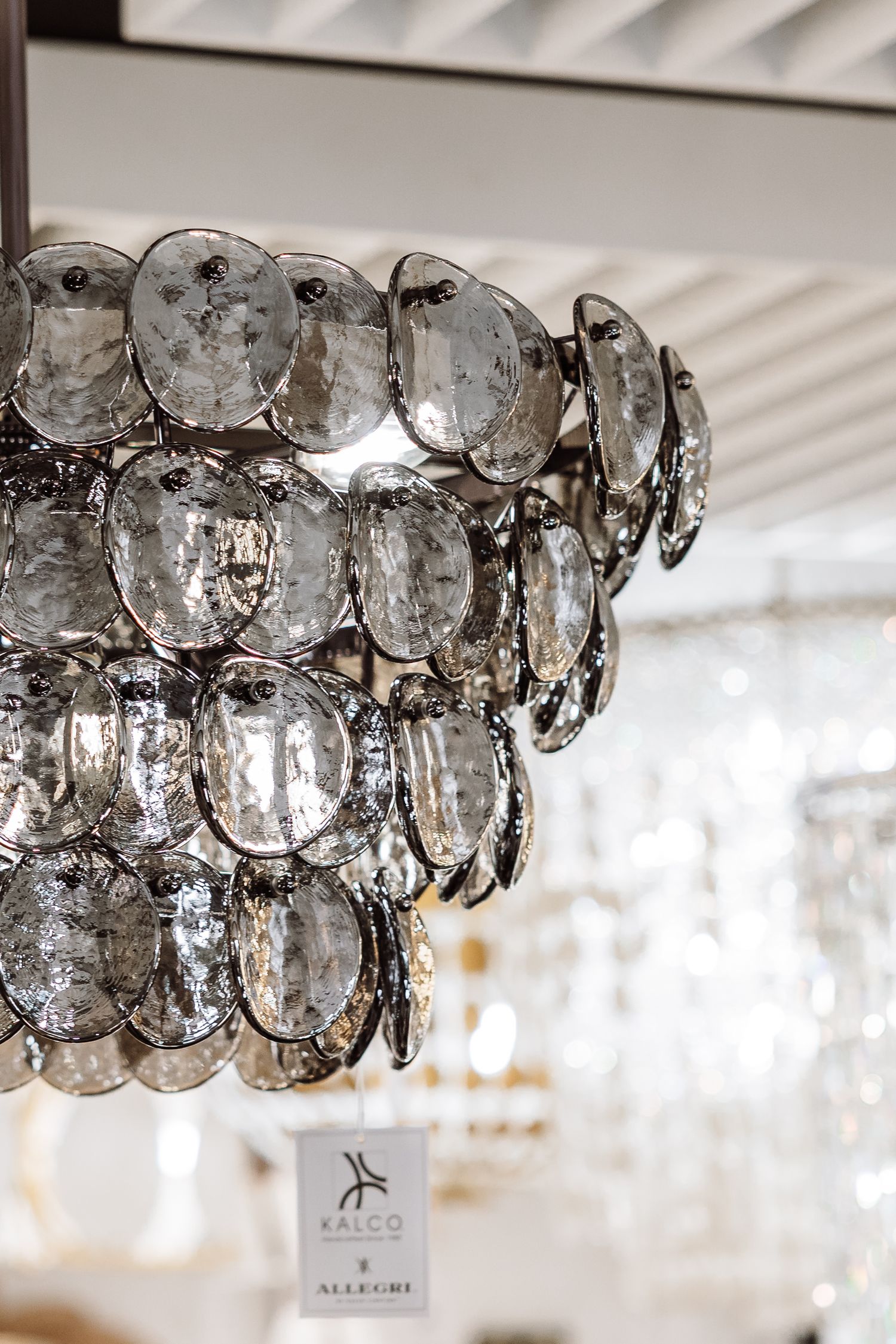 A close-up of an elegant Kalco Allegri chandelier featuring layered smoky glass disc pendants.