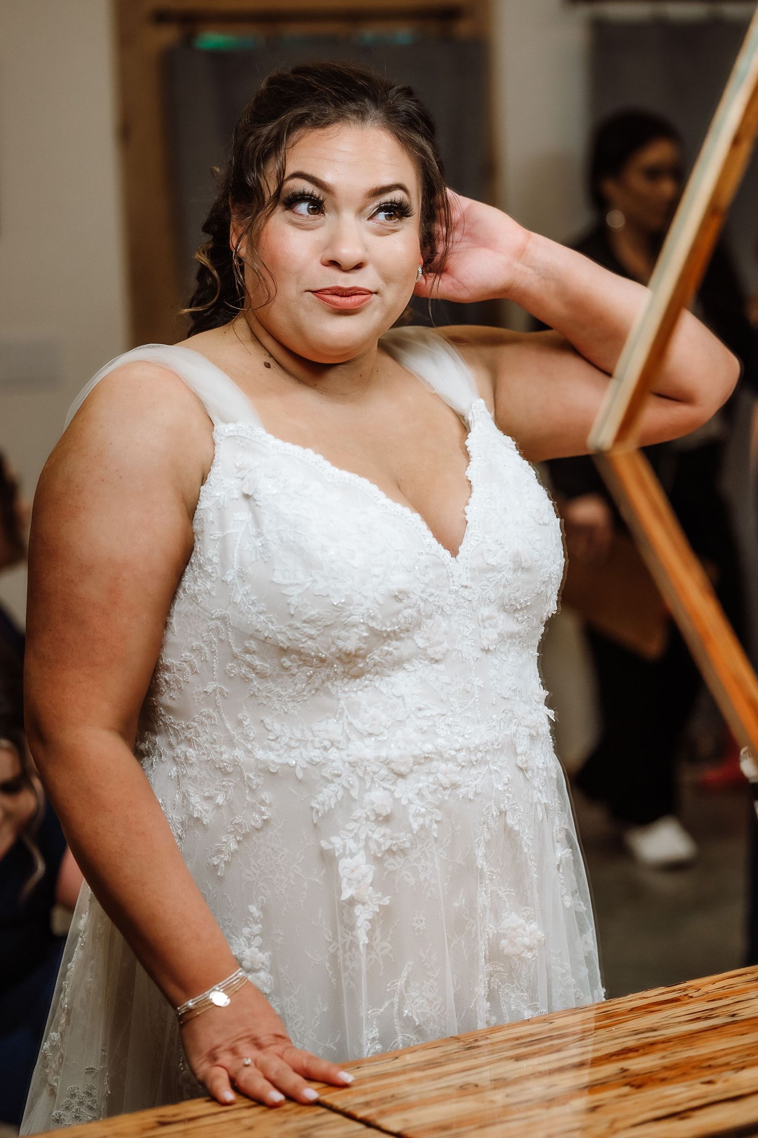 Beautiful bride in a white lace wedding gown posing elegantly at her wedding reception.