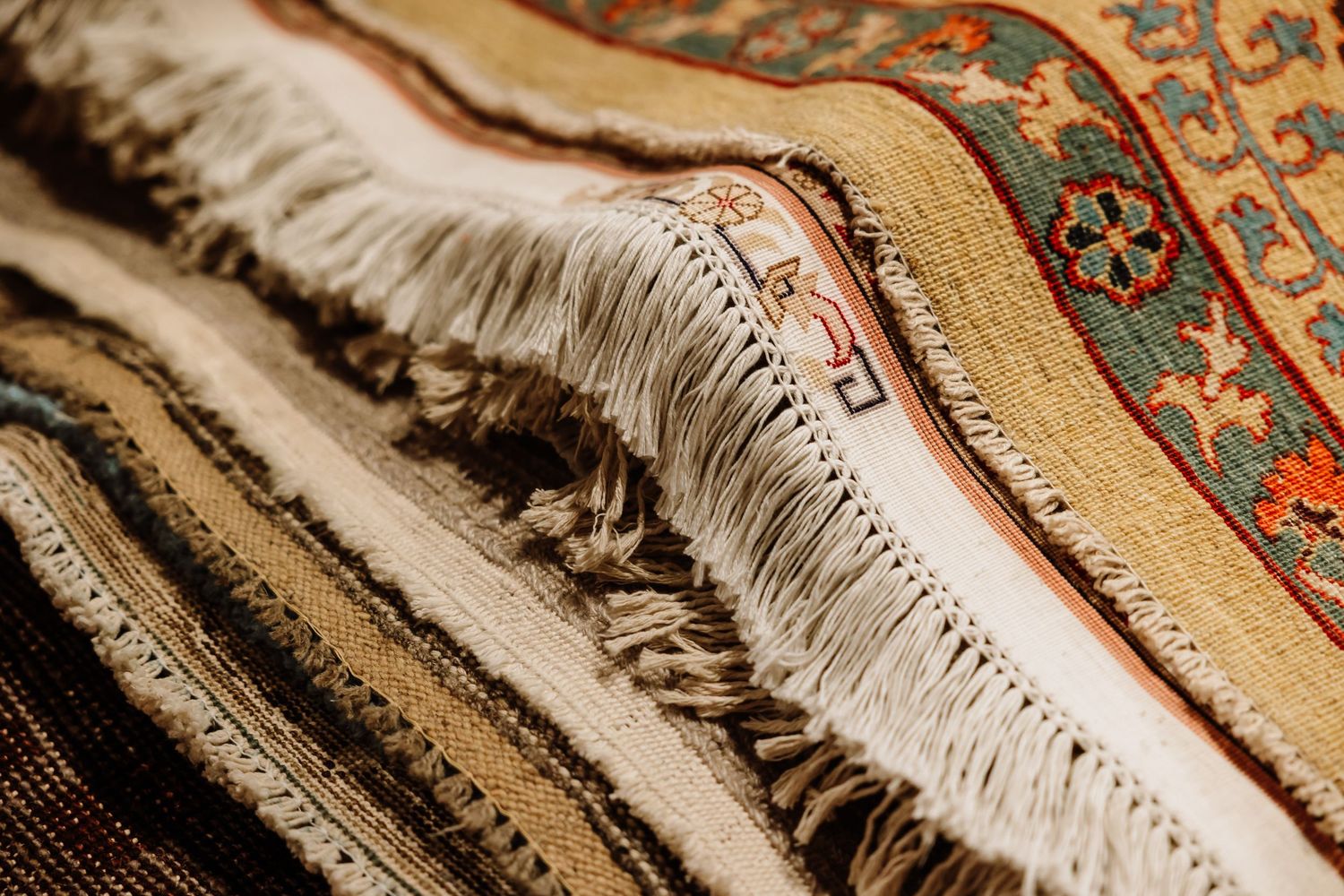 Close-up of layered oriental rugs with decorative fringe and intricate woven patterns.