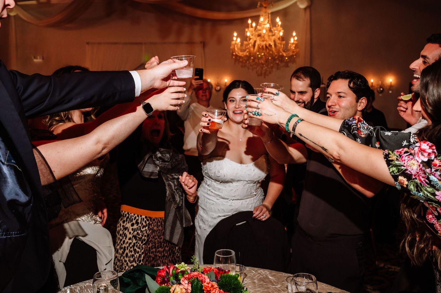 Bride and wedding guests clinking glasses together in a joyful toast at the reception dinner.