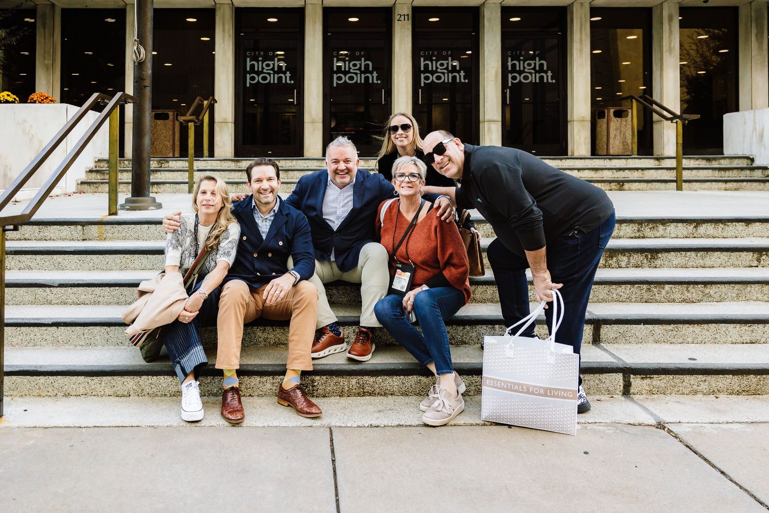 Group of five people smiling on steps outside High Point Market entrance.