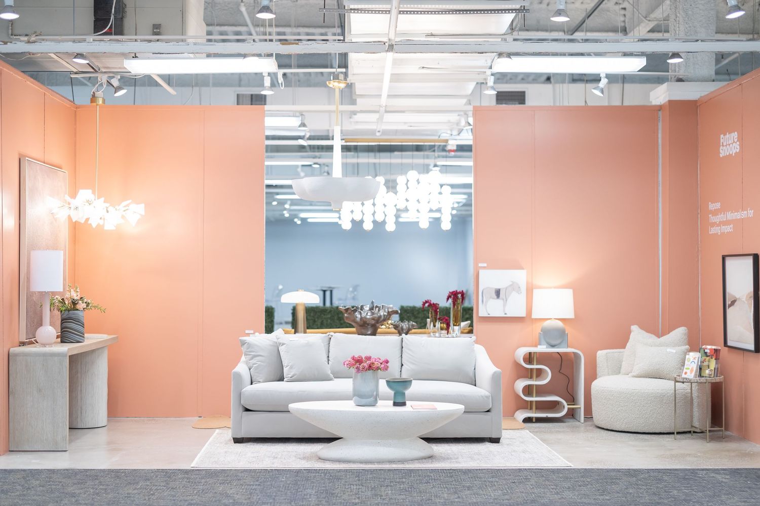 Modern furniture showroom with peach walls displaying white sofas, chairs, and elegant chandeliers.