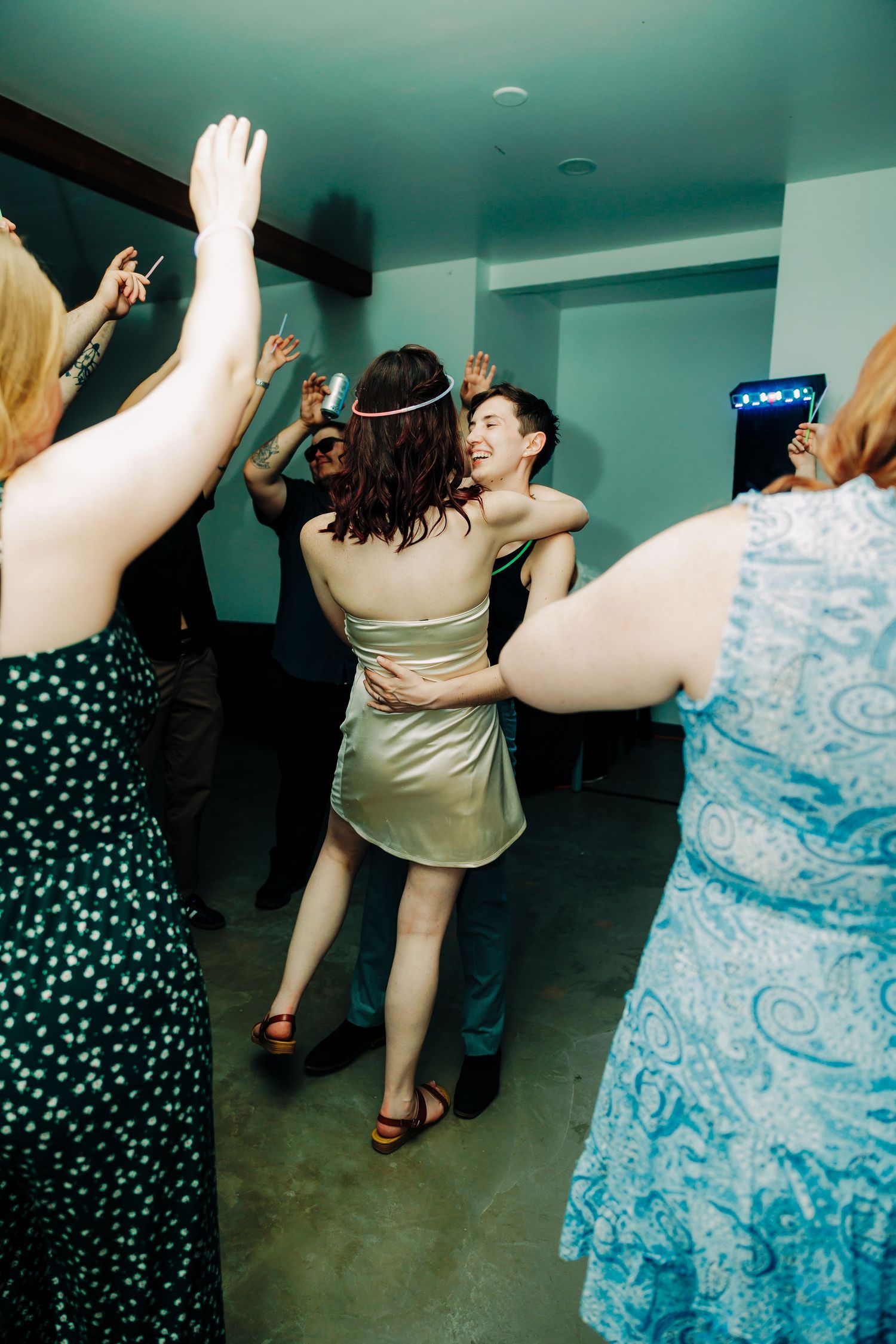 Couple dancing closely and smiling together on a crowded wedding reception dance floor.