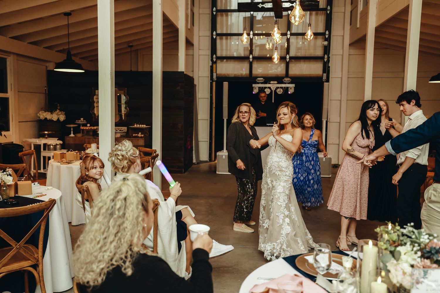 Bride gives speech in elegant venue while guests listen at decorated reception tables.