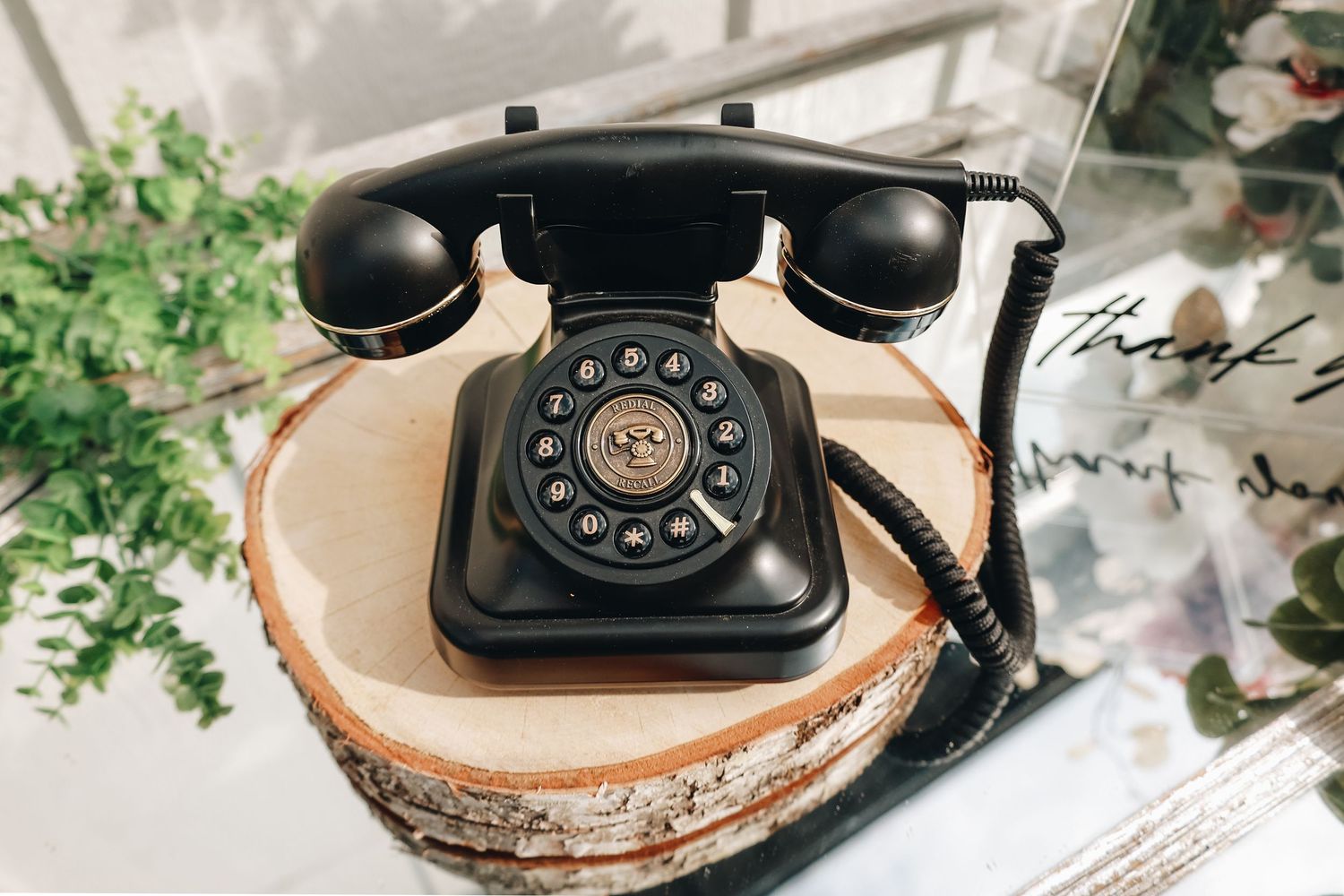Vintage black rotary telephone on a wood slice at an elegant wedding reception decoration display.
