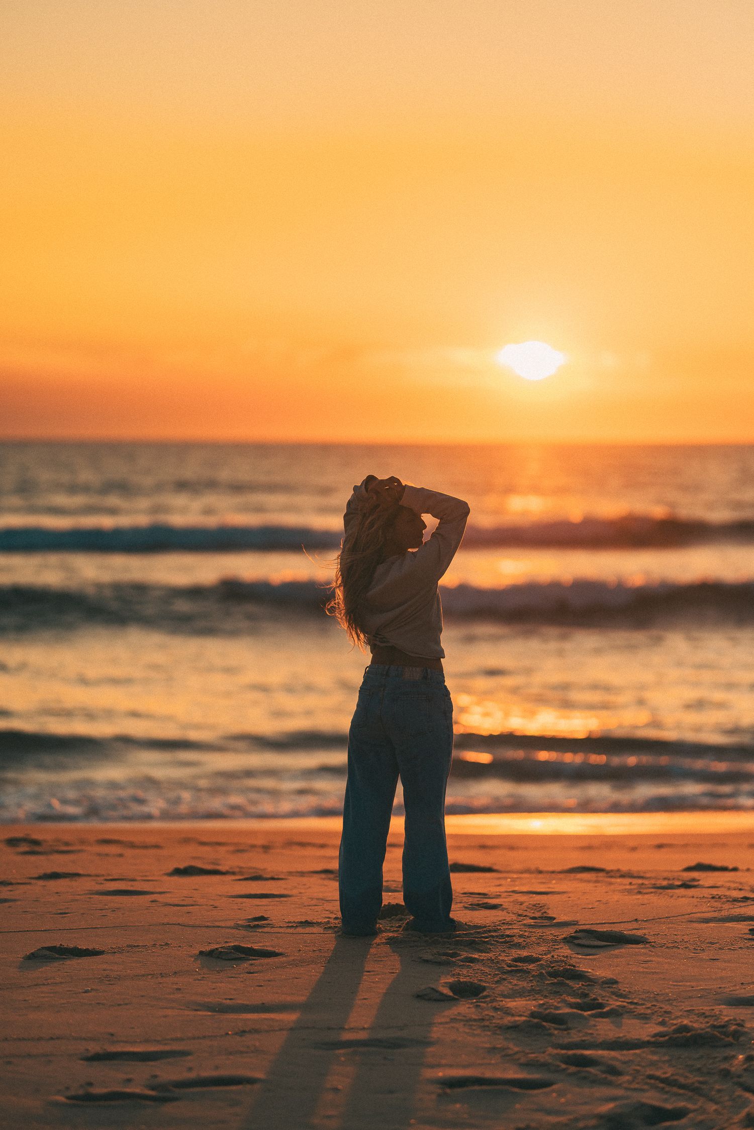 Silhouette d'une personne s'étirant sur la plage pendant un coucher de soleil orange vif.