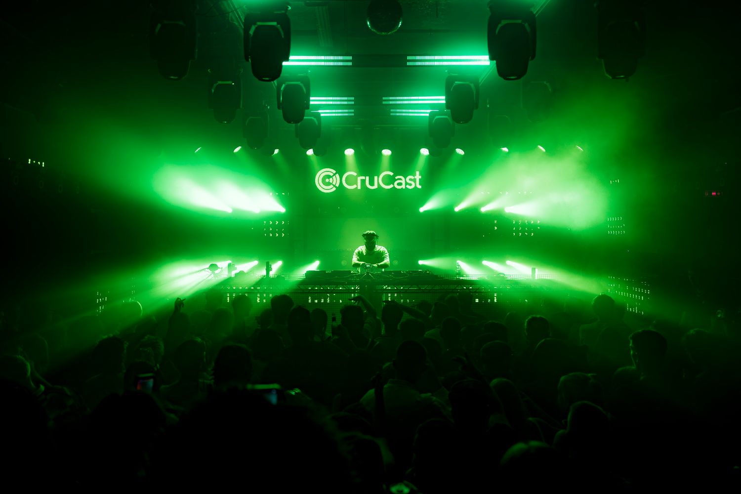 Concert stage illuminated with bright green lighting and fog effects creates an atmospheric performance environment.