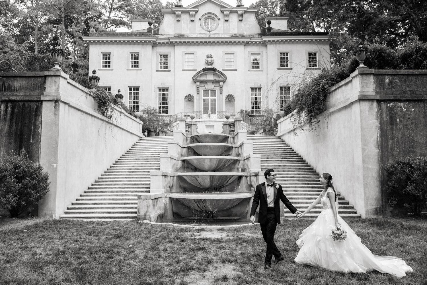 A sequence of black and white wedding photos showing a couple at a grand estate with elegant staircases and architecture.