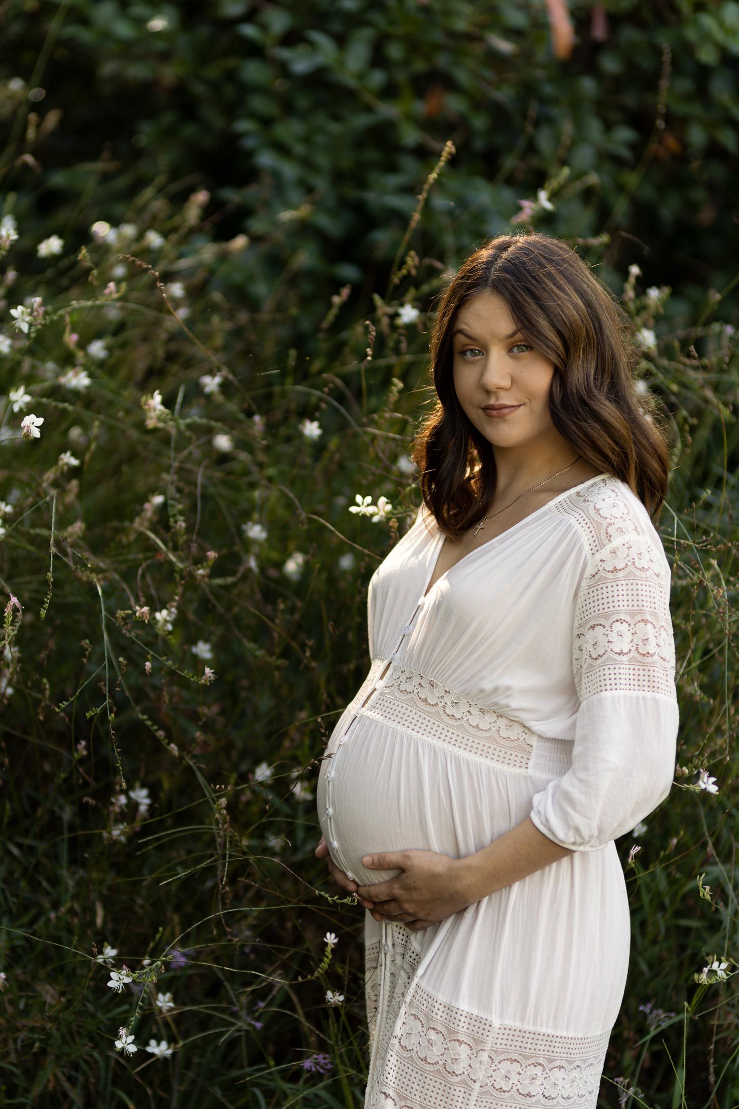 Beautiful image by Nick Wigmore Photography of pregnant woman in white dress among flowers.