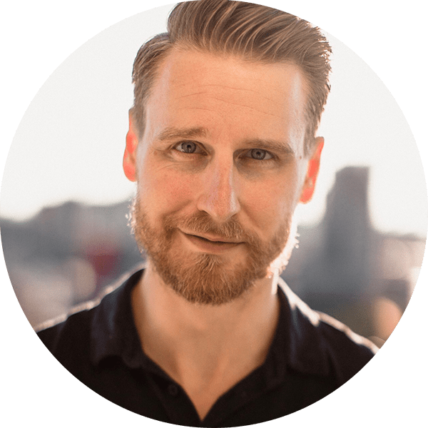 Professional headshot portrait with city skyline background.