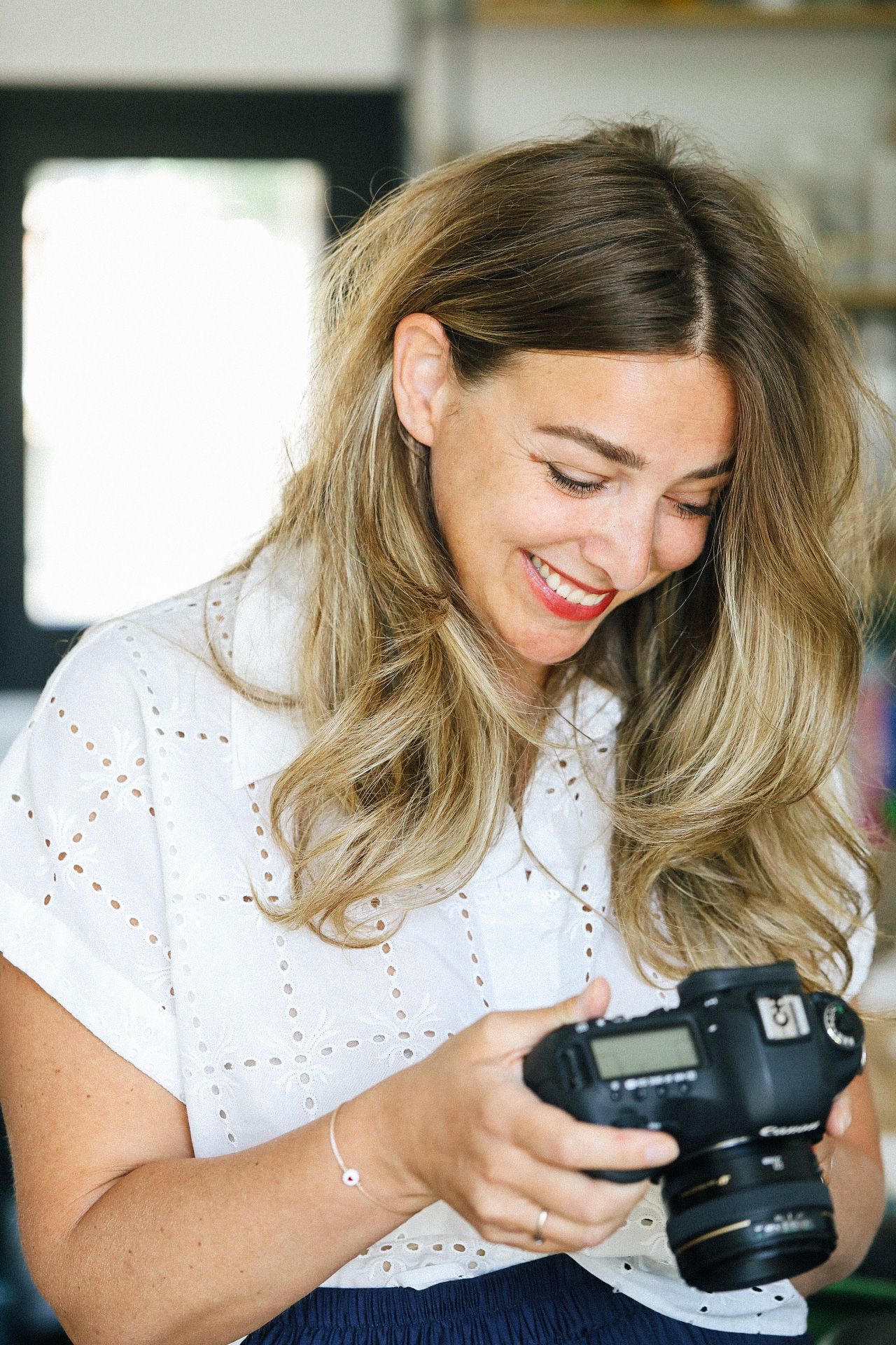 Looking down at a DSLR camera display screen while smiling.