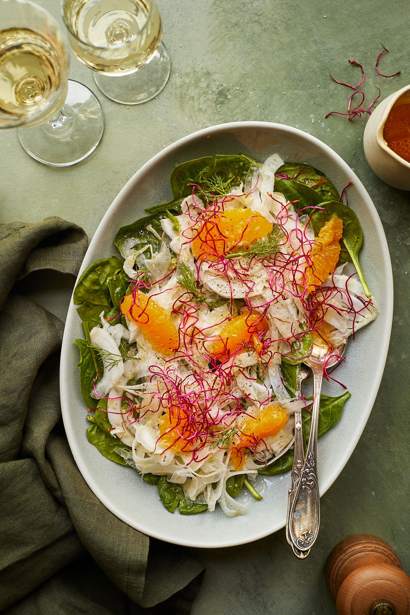 Elegant citrus and fennel salad with wine glasses and table setting.