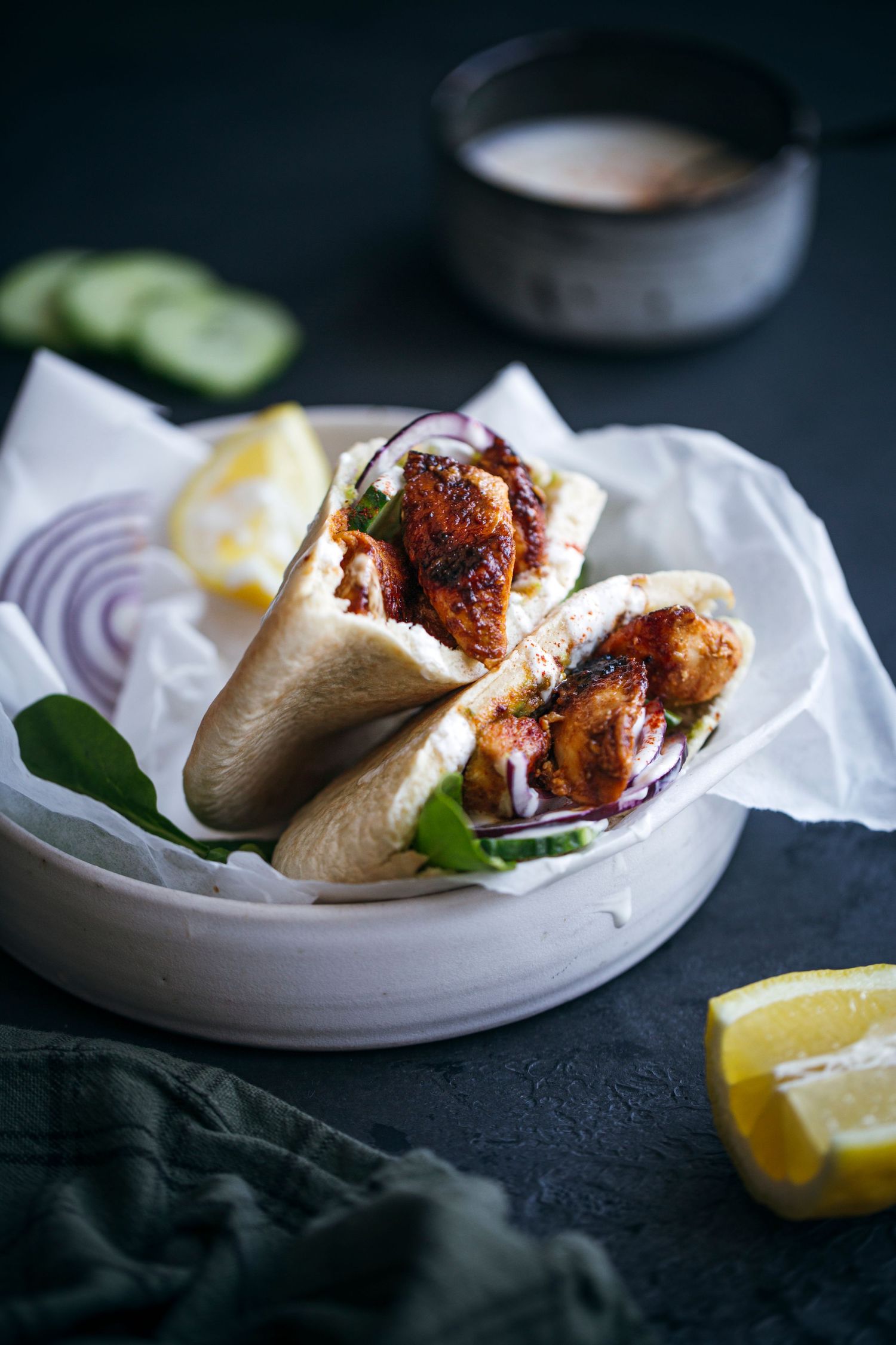 Two chicken wraps with lettuce and lemon wedges served on white ceramic plate.