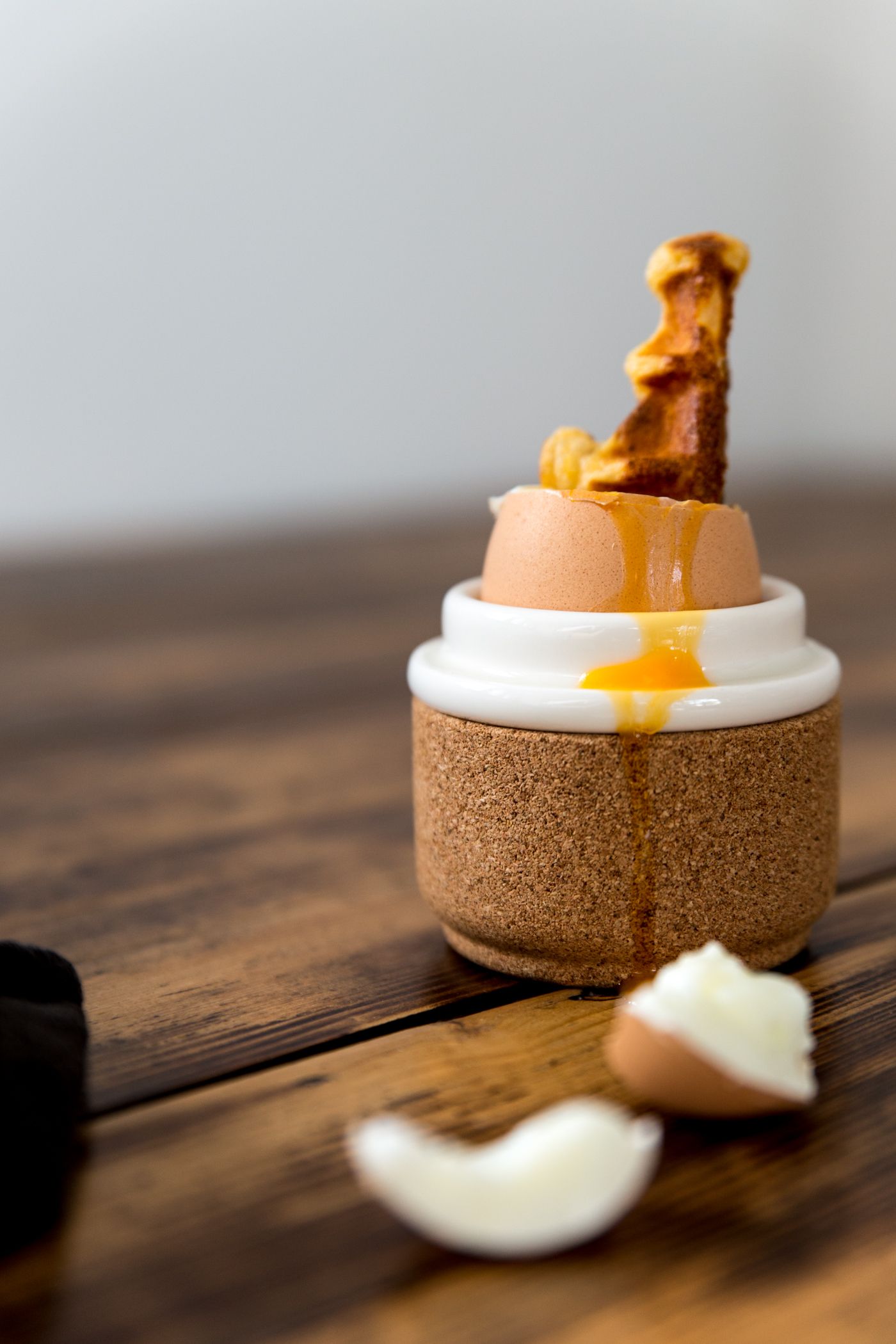 Soft boiled egg in cork holder with running yolk and toast soldiers.