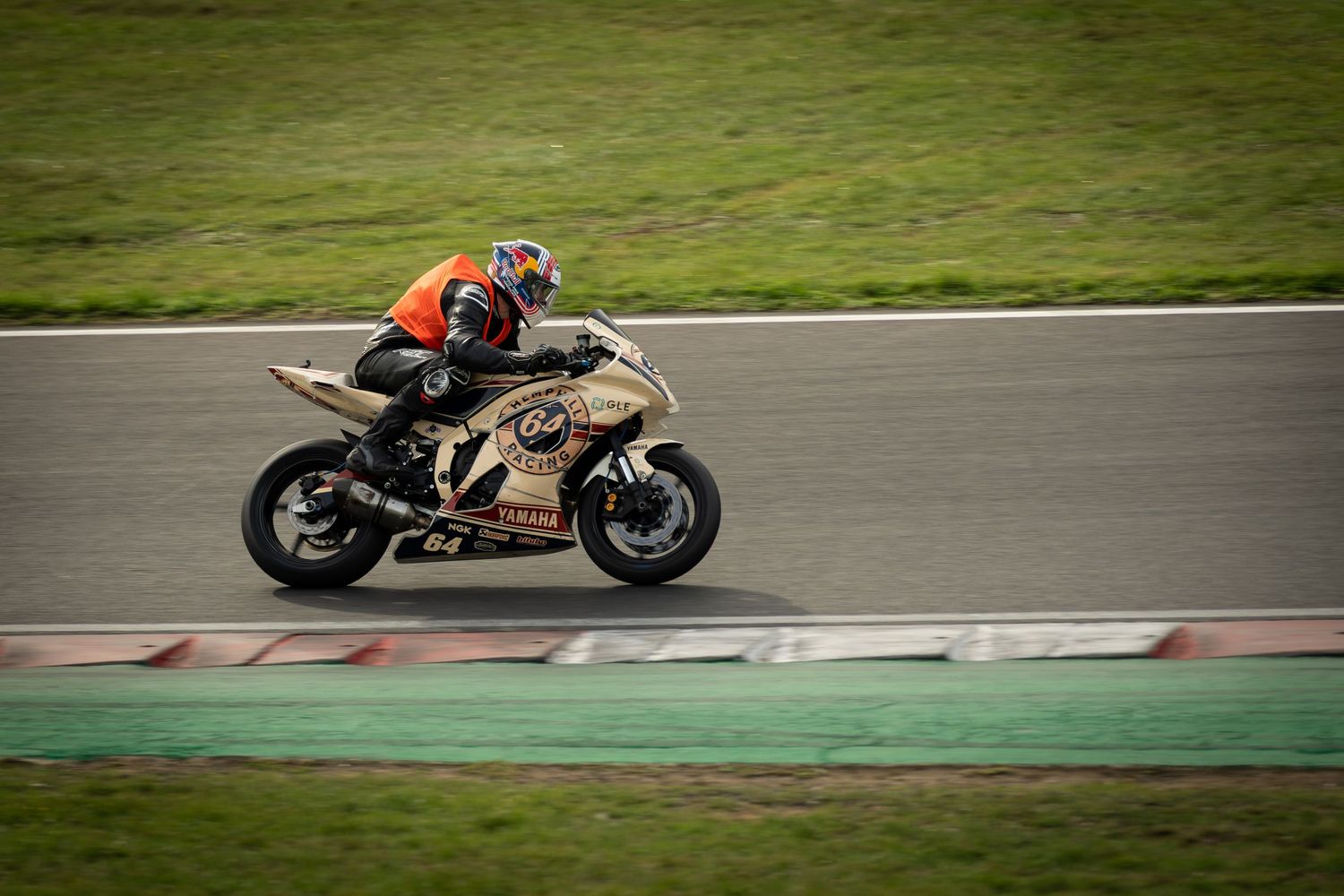Motorcycle racer leaning into a turn on a racing circuit during a professional track event.