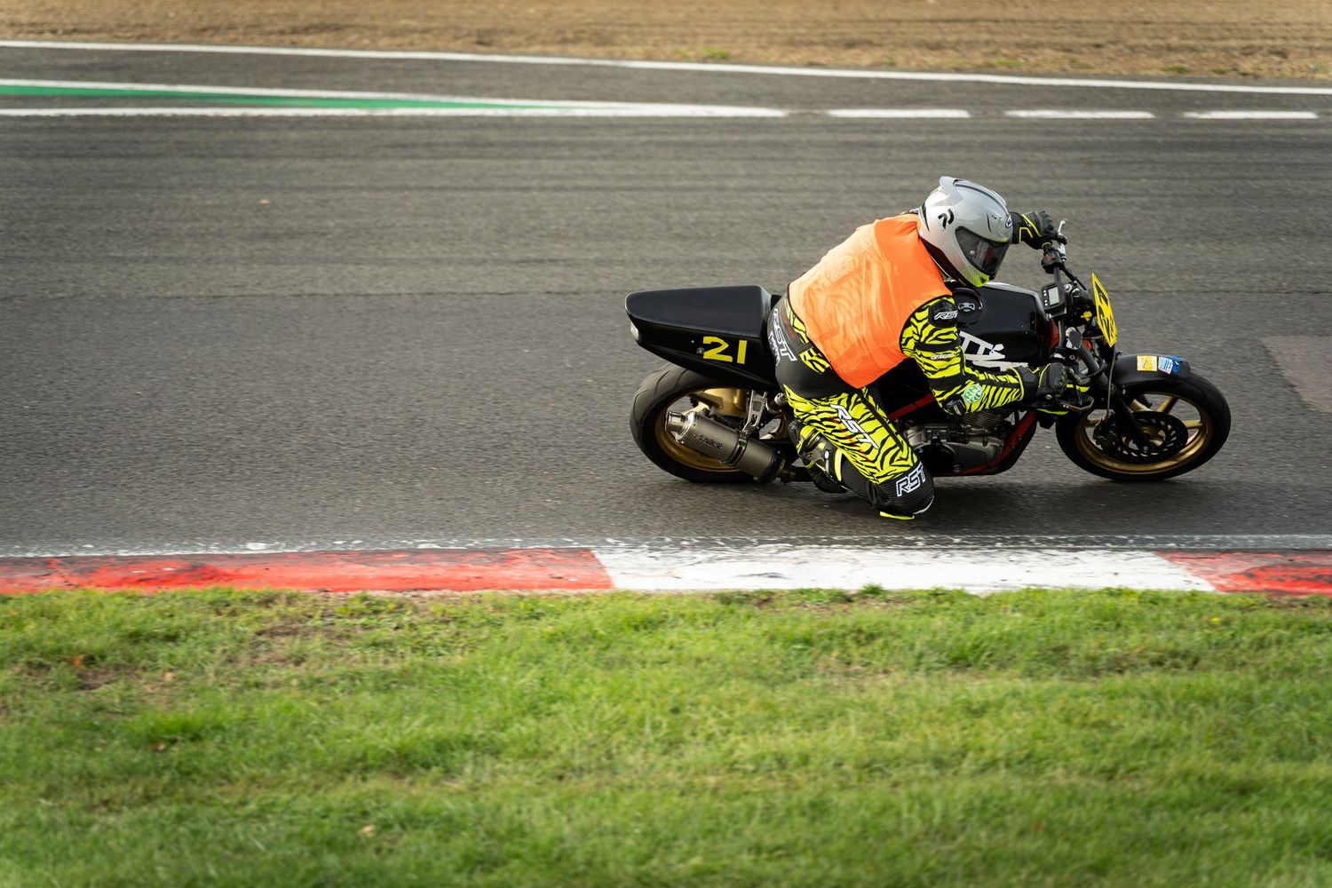 Motorcycle racer in yellow gear cornering at high speed on a professional racing circuit.