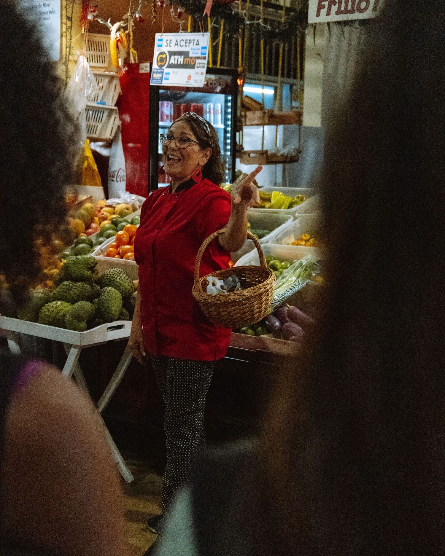 A woman shopping for vegetables at an open market stops to give tourists directions.