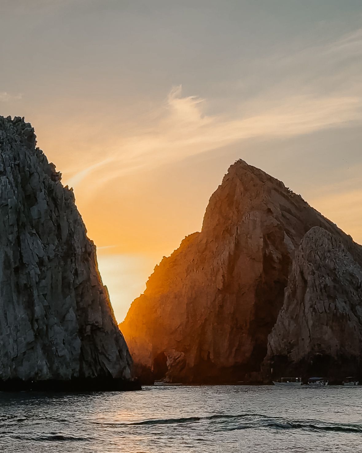 Sunset sets the sky ablaze behind two darkened mountain peaks.