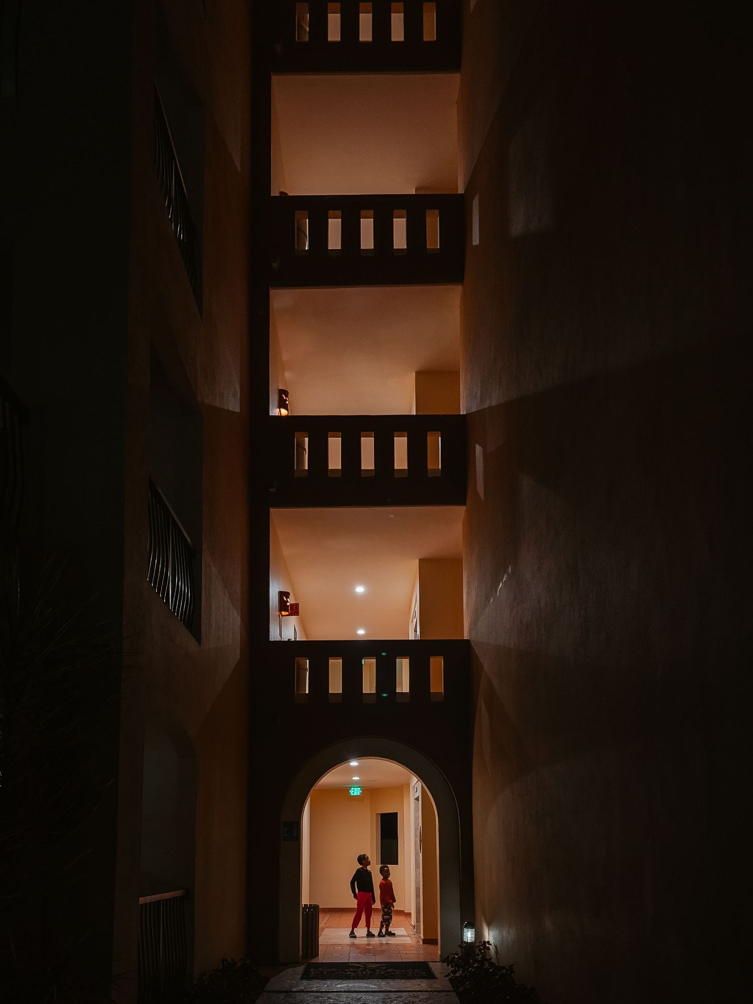 Two children wait at the elevator of a high-rise hotel.