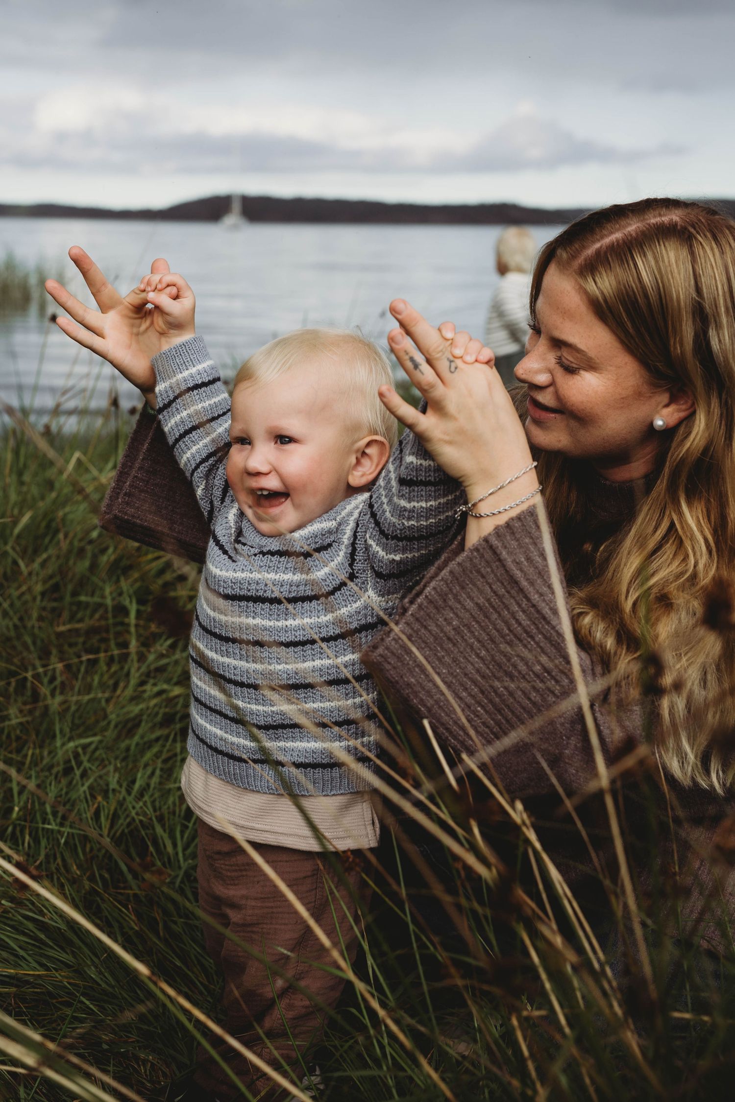 Glad pojke med händerna upp i luften med sin mamma.