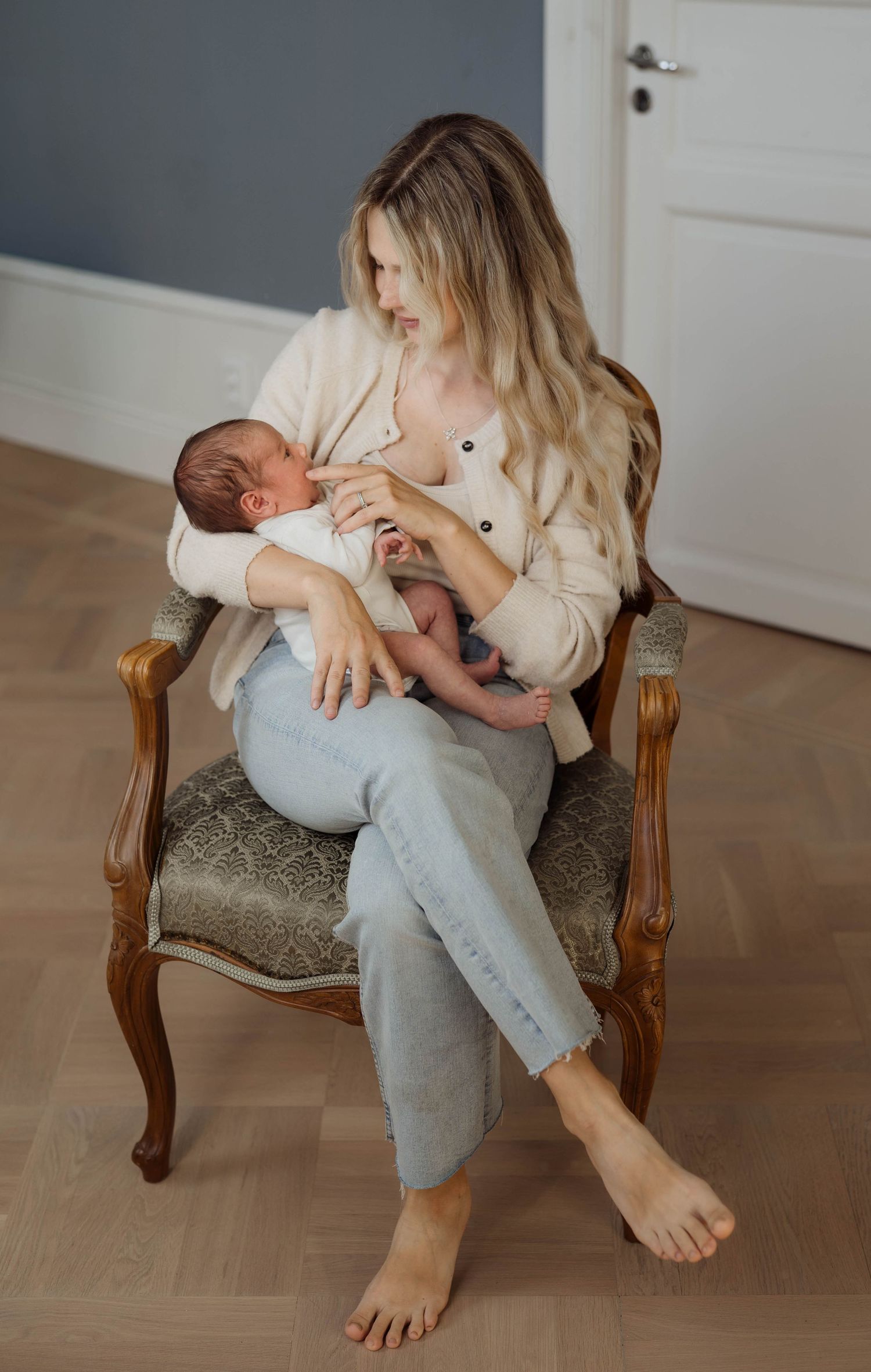 Mamma sittandes i stol med nyfödd bebis i famnen.