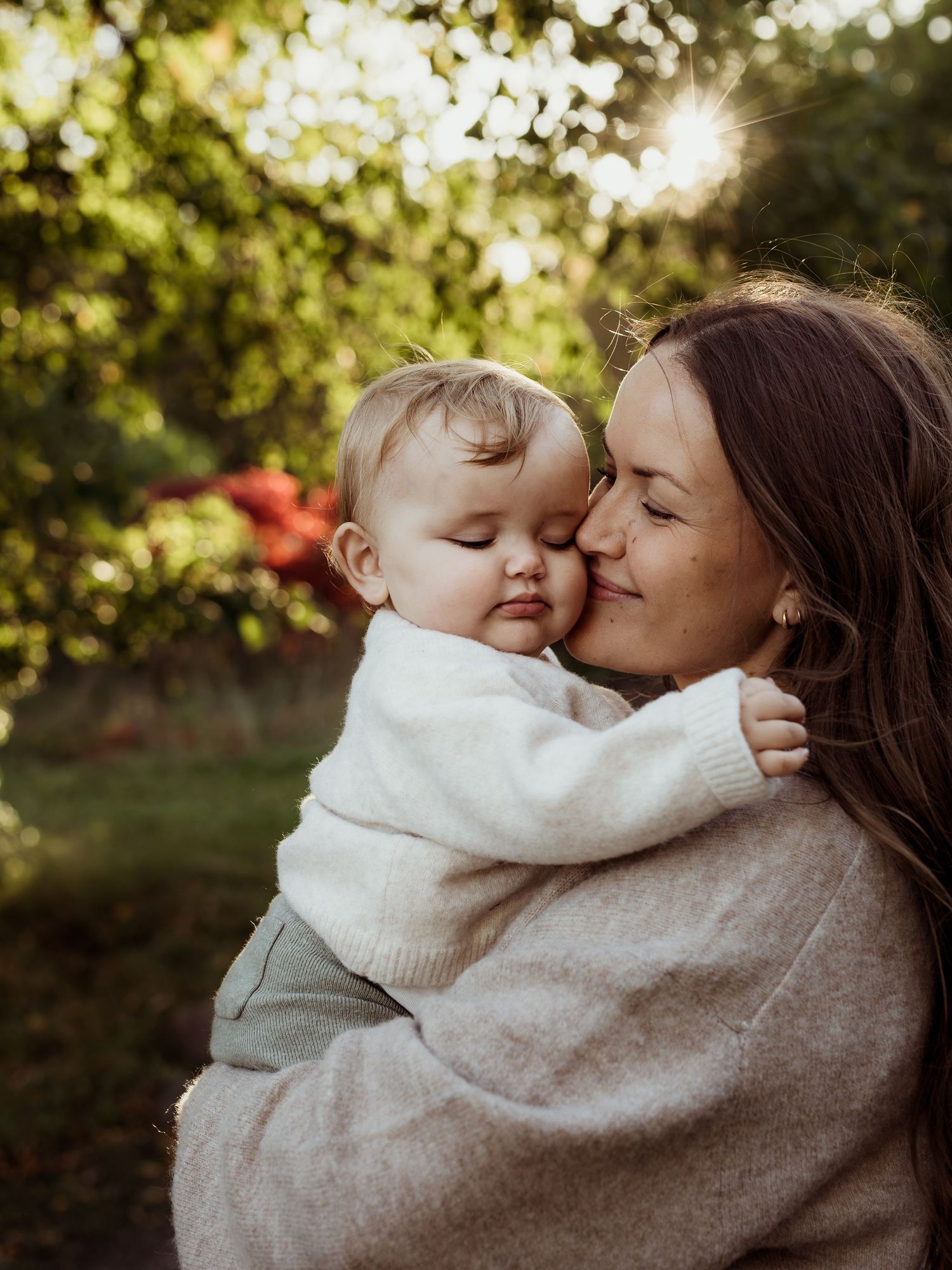 Mamma kramandes med dotter i famnen och leer.