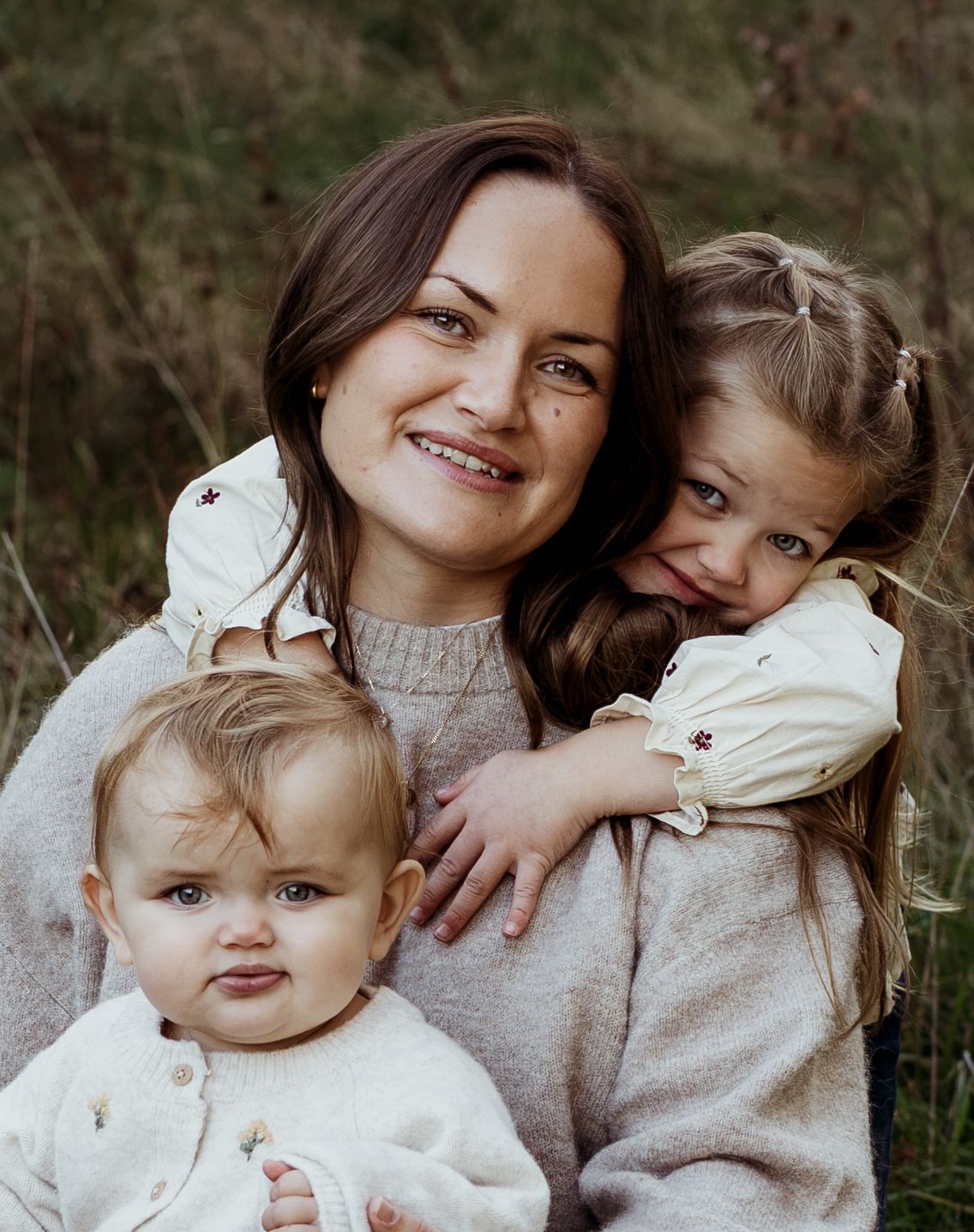 Mamma med flicka bakom kramandes och liten flicka i knät