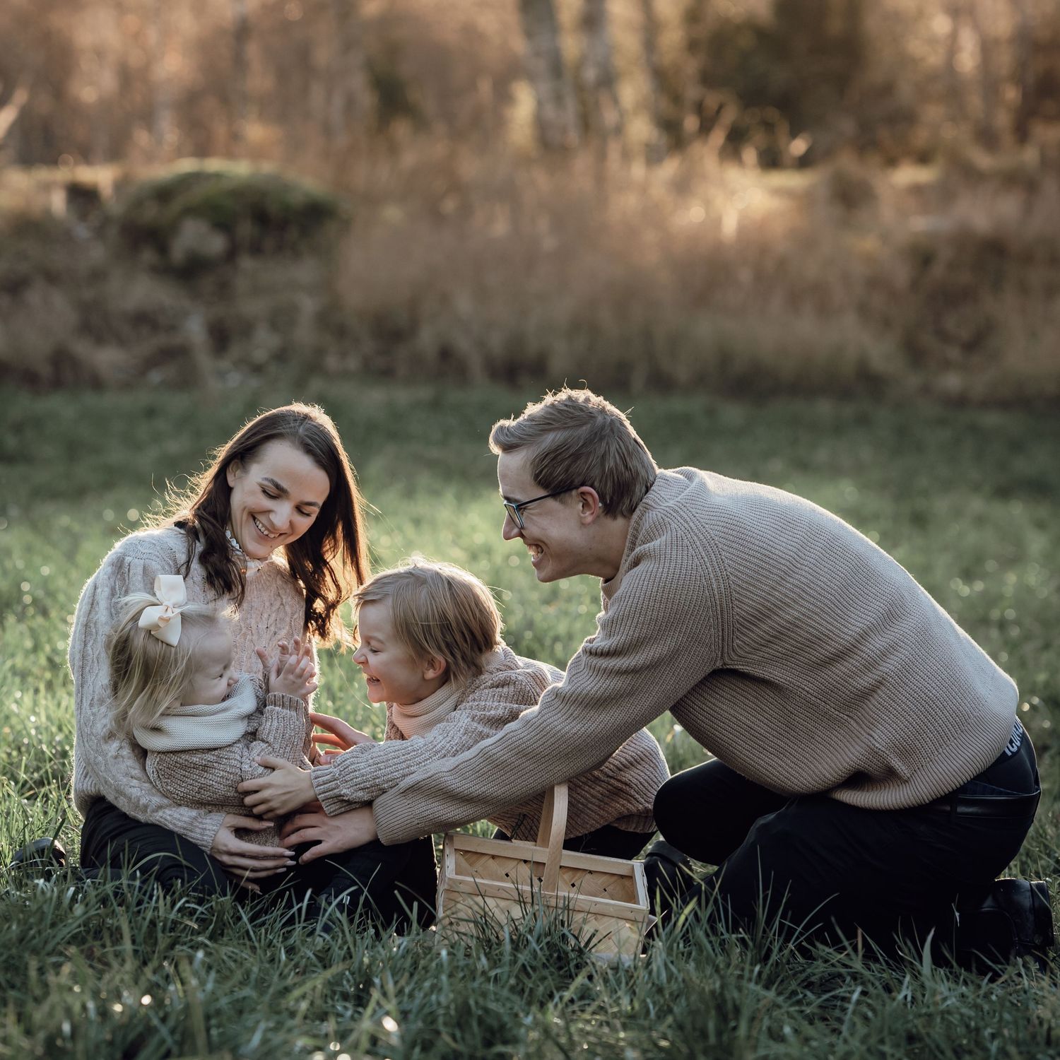 Familj på en picknickfilt på en äng. Mamma pappa storebror och lillasyster