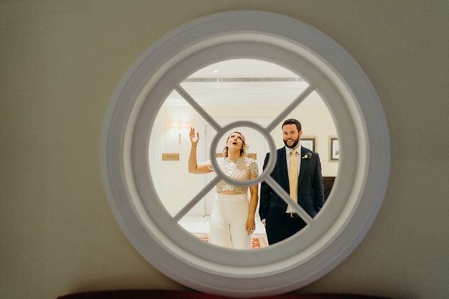 A bride and groom framed through a round window