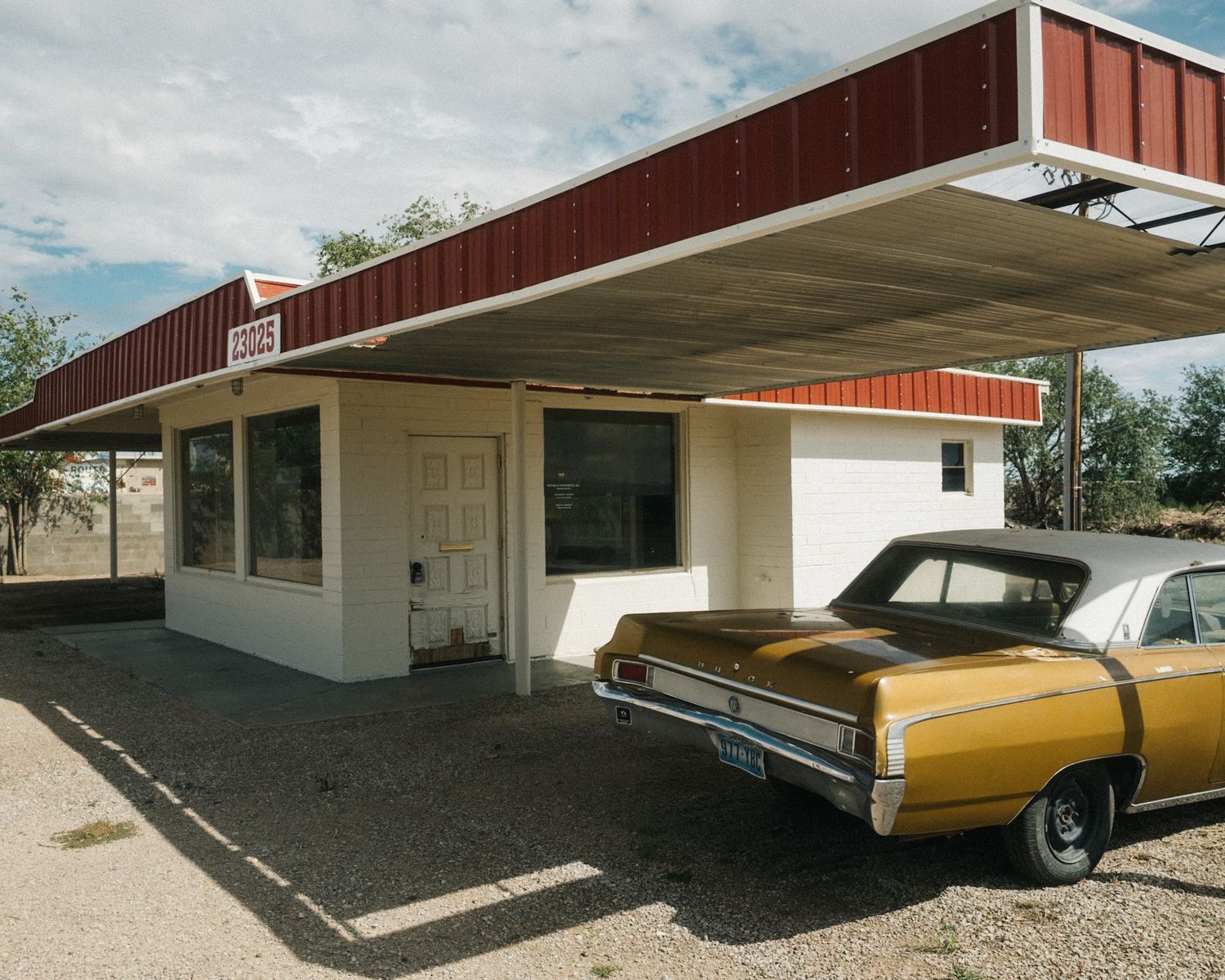 Roadside building with a red roof and a vintage gold car parked in front