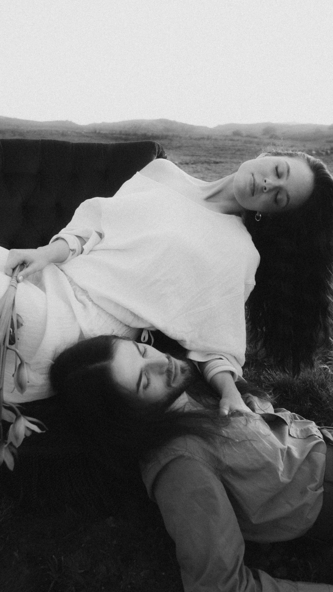 Black and white photo of a couple lying back together in a relaxed, candid moment.