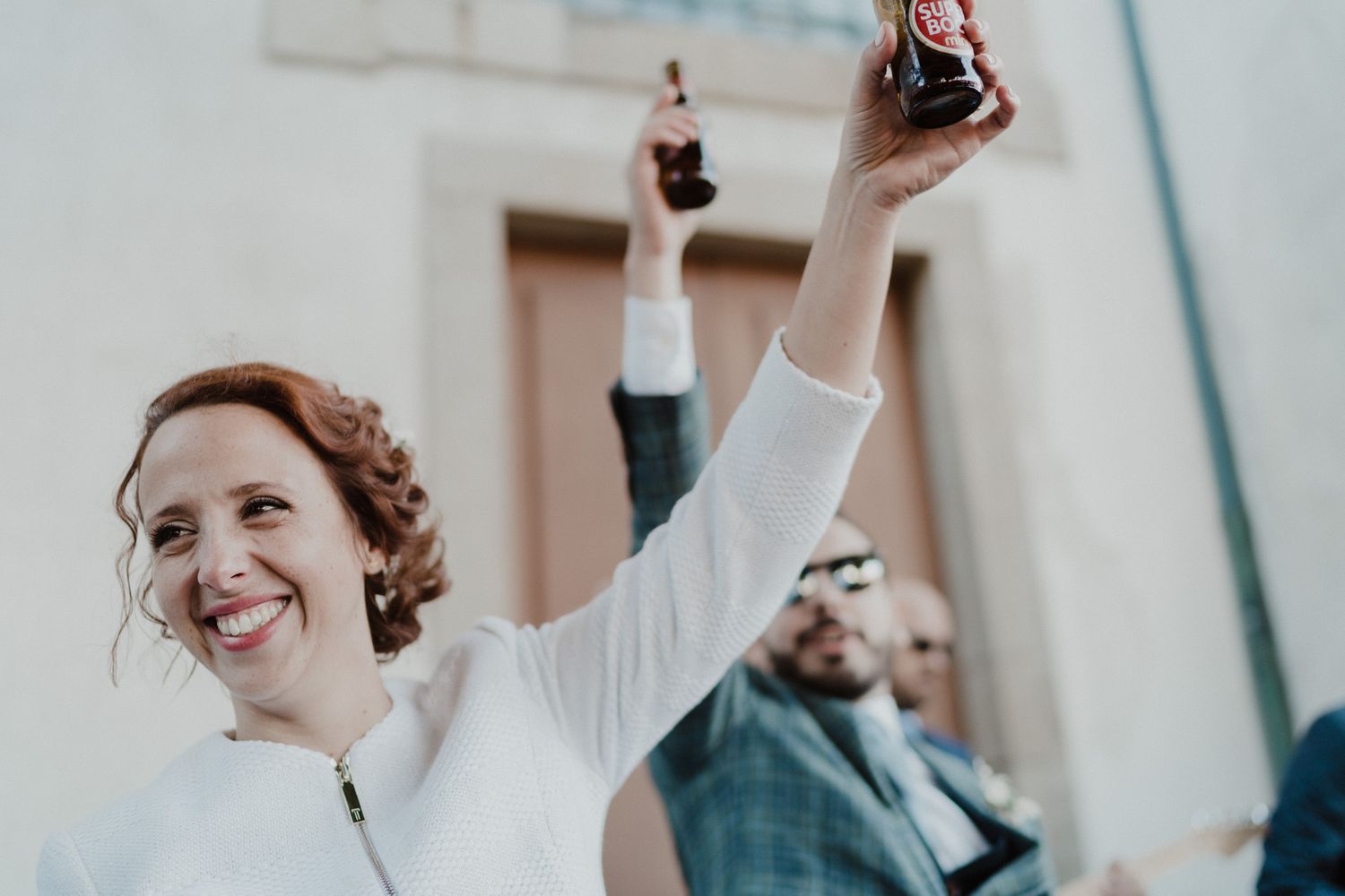 Bride celebrating joyfully during an intimate wedding in Porto, with a superbock beer
