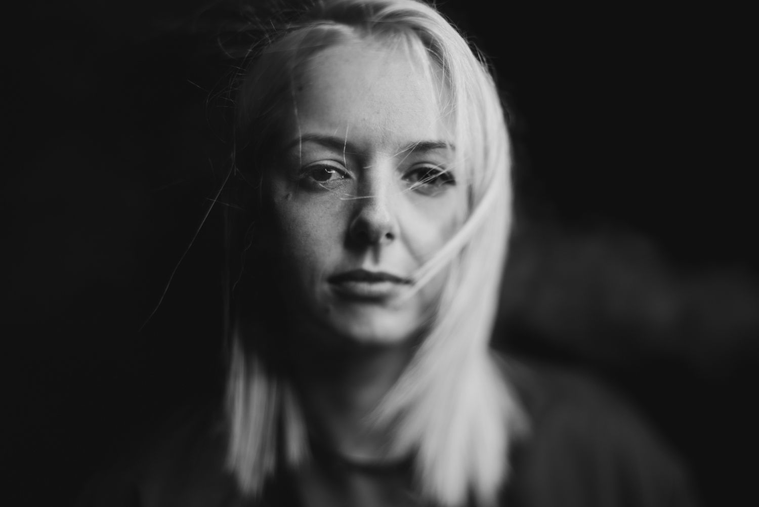 Black and white close-up portrait of a woman with blonde hair looking into the camera
