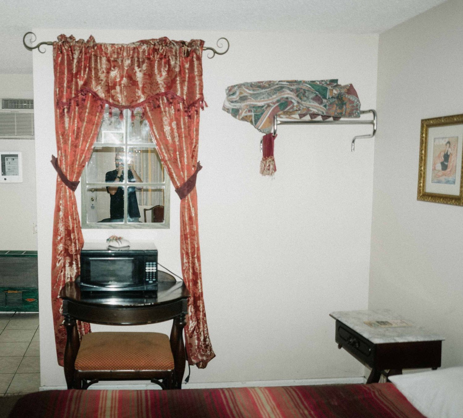 Hotel room with red patterned curtains, a small table and a picture on the wall