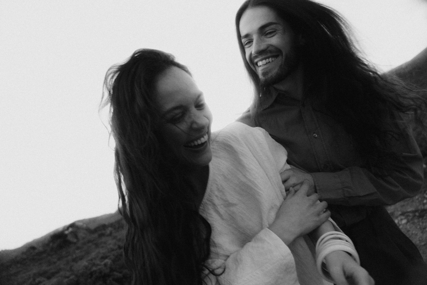 Black and white close-up of a couple laughing together outdoors.