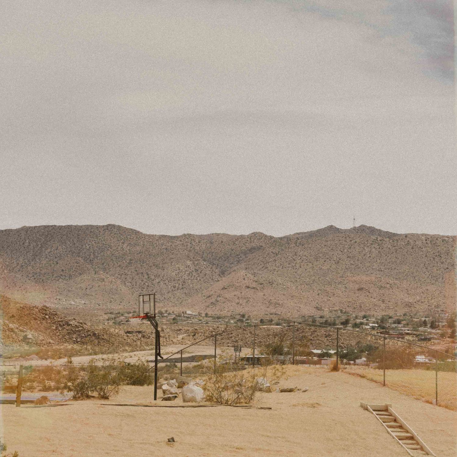 Warm-toned view of desert mountains and a small town from a hillside road
