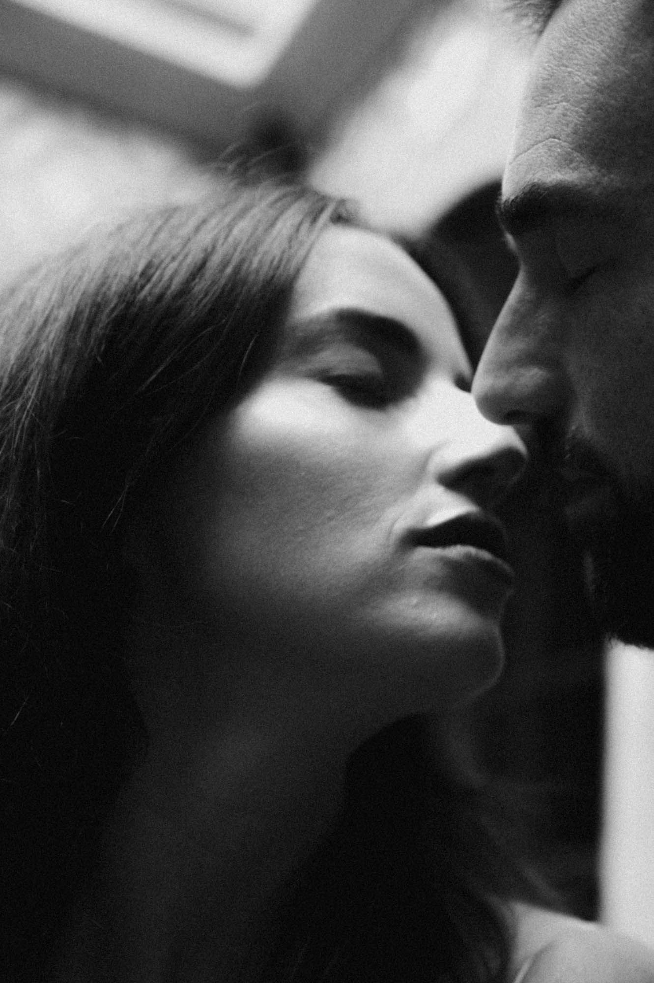Black and white close portrait of a couple with eyes closed, foreheads together