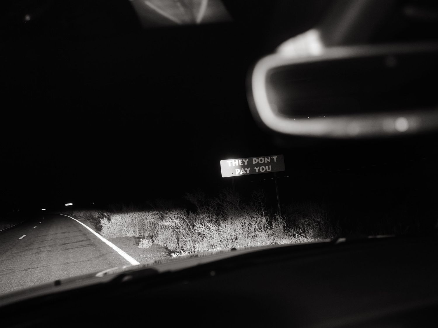 Black and white night photo of a road seen through a car windscreen