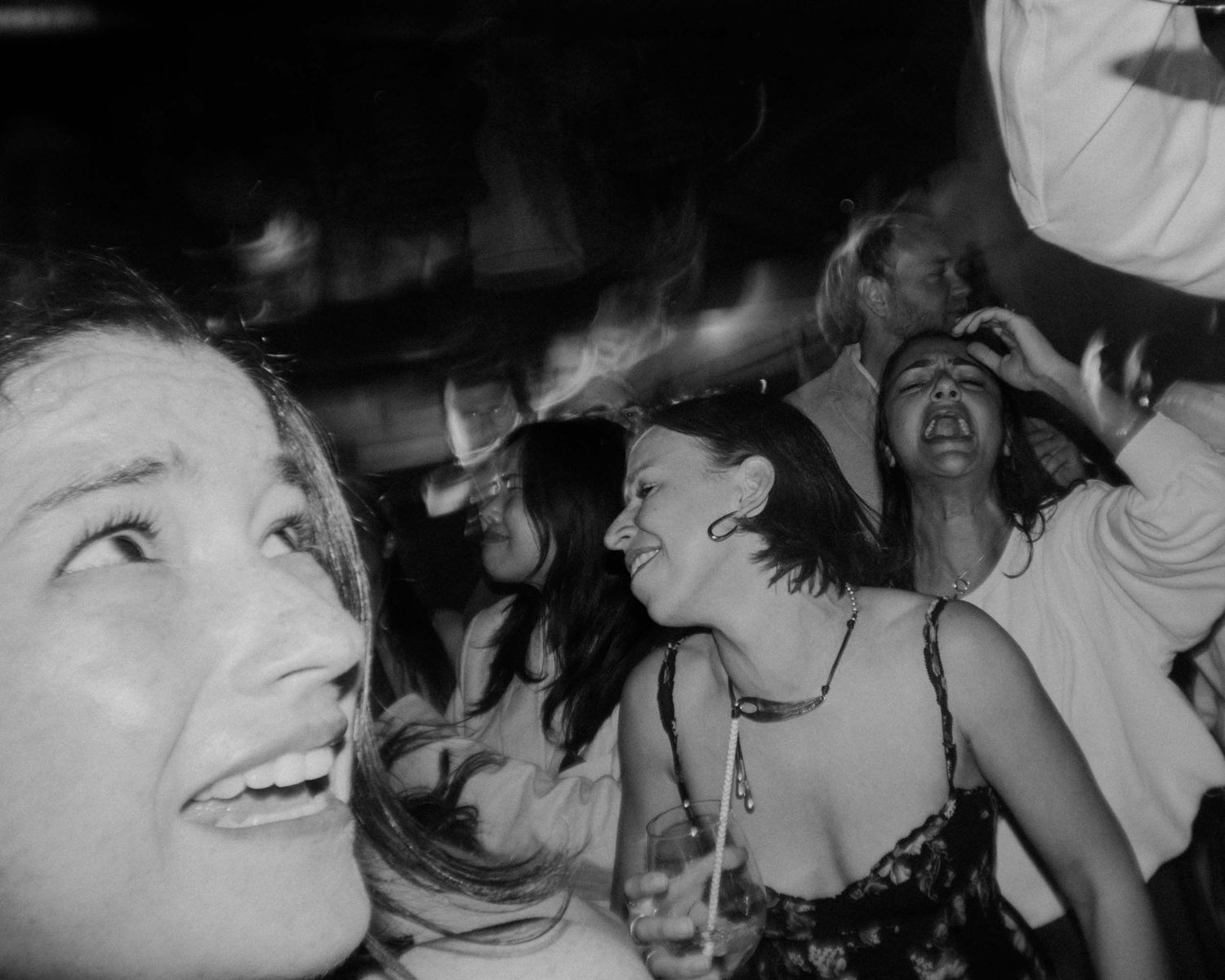 Black and white photo of guests singing and laughing on a crowded dance floor