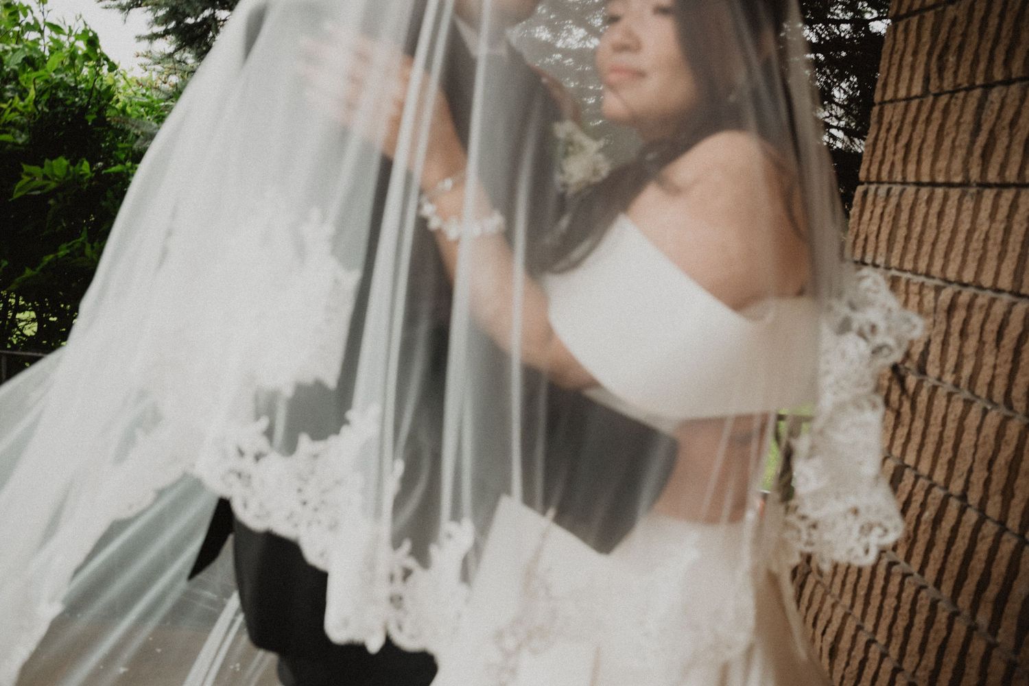 Romantic close-up of bride and groom sharing an intimate moment beneath a lace-trimmed wedding veil.