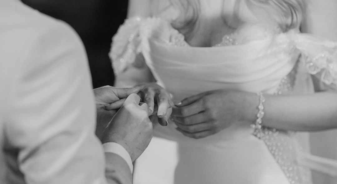 Black and white close-up of wedding rings being exchanged