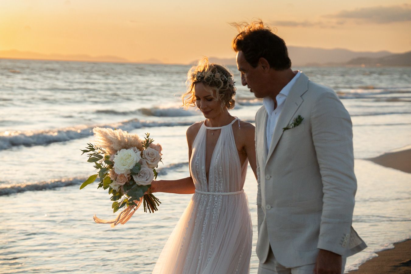 Wedding couple walking on a beach in Tuscany at sunset
