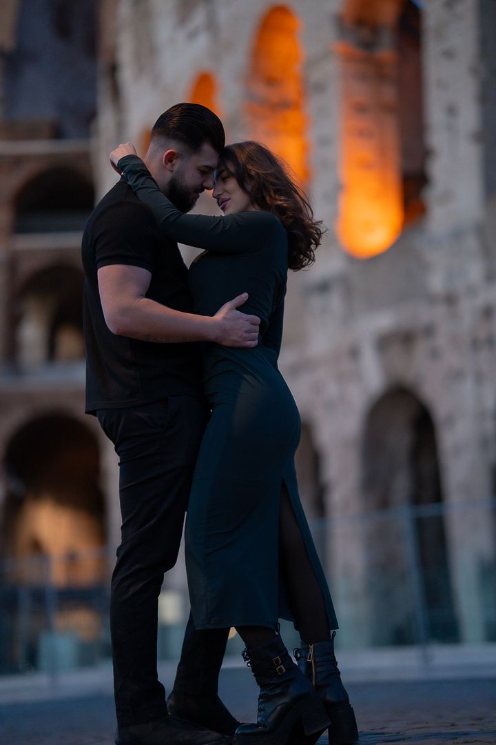Couple embracing in front of Colosseum during an evening photo session in Rome