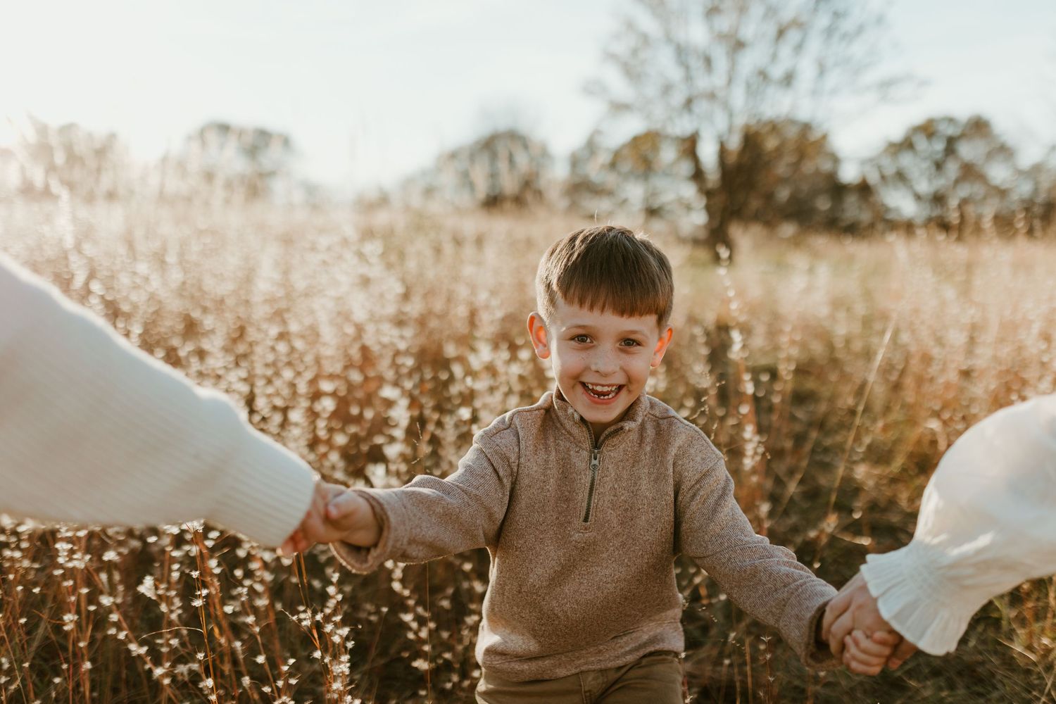 Spartanburg family photo session by PhotosbyAllii in a field. A smiling boy enjoying the moment, captured having fun in a natural, relaxed
