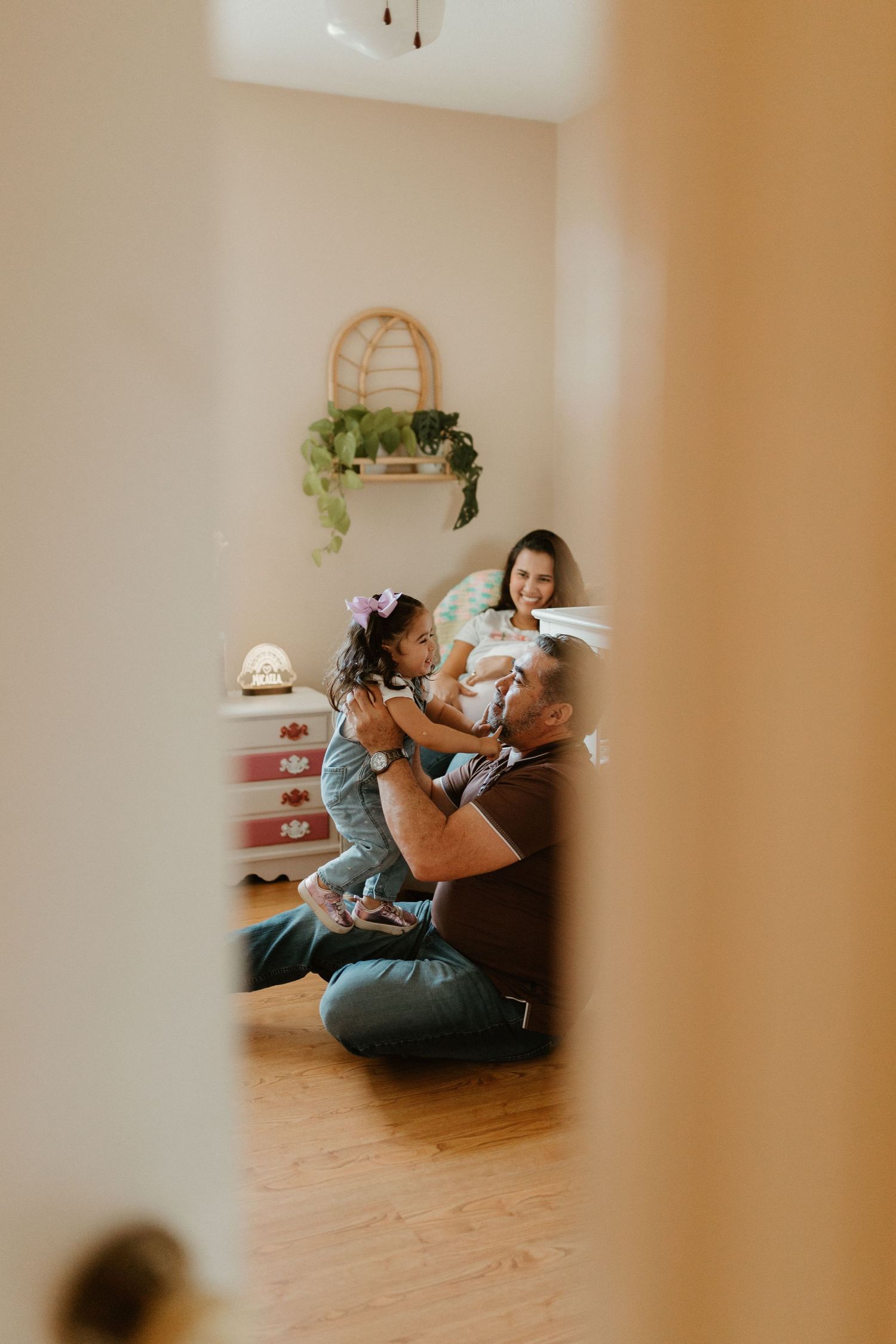 A series of progressive images showing a family playing with a toddler and angle is peaking through a bedroom door. In-home family session