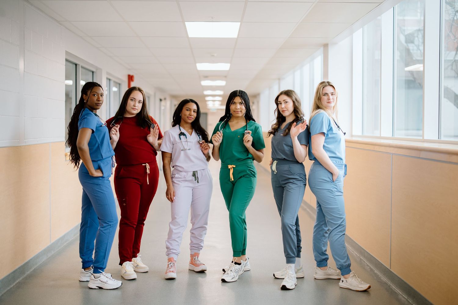 Healthcare workers in colorful scrubs walk down a bright hospital hallway during their shift.