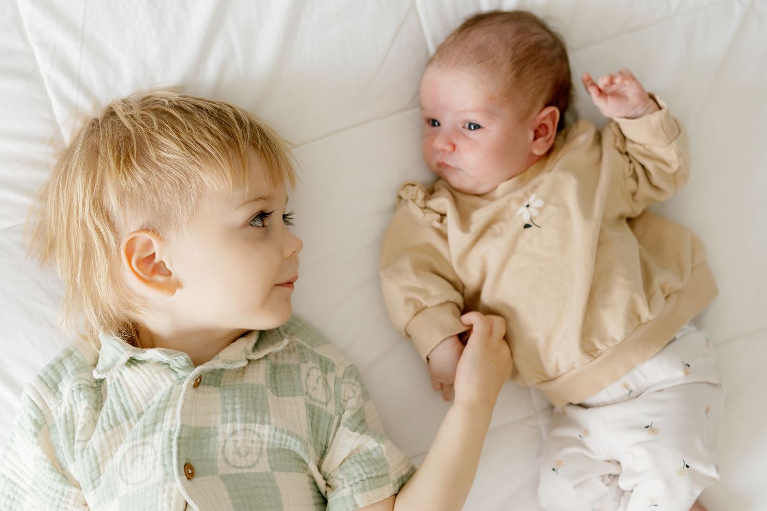 A series of tender black and white photos showing a baby and parent sharing sweet moments together on a bed.