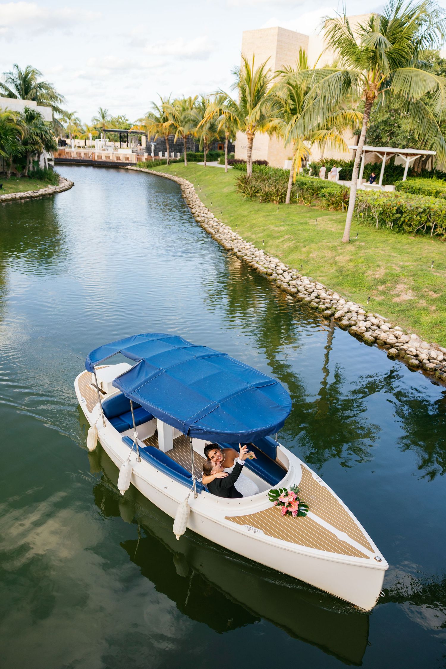 A series of photos showing an electric boat with blue canopy cruising along a waterway lined with palm trees and rocks.