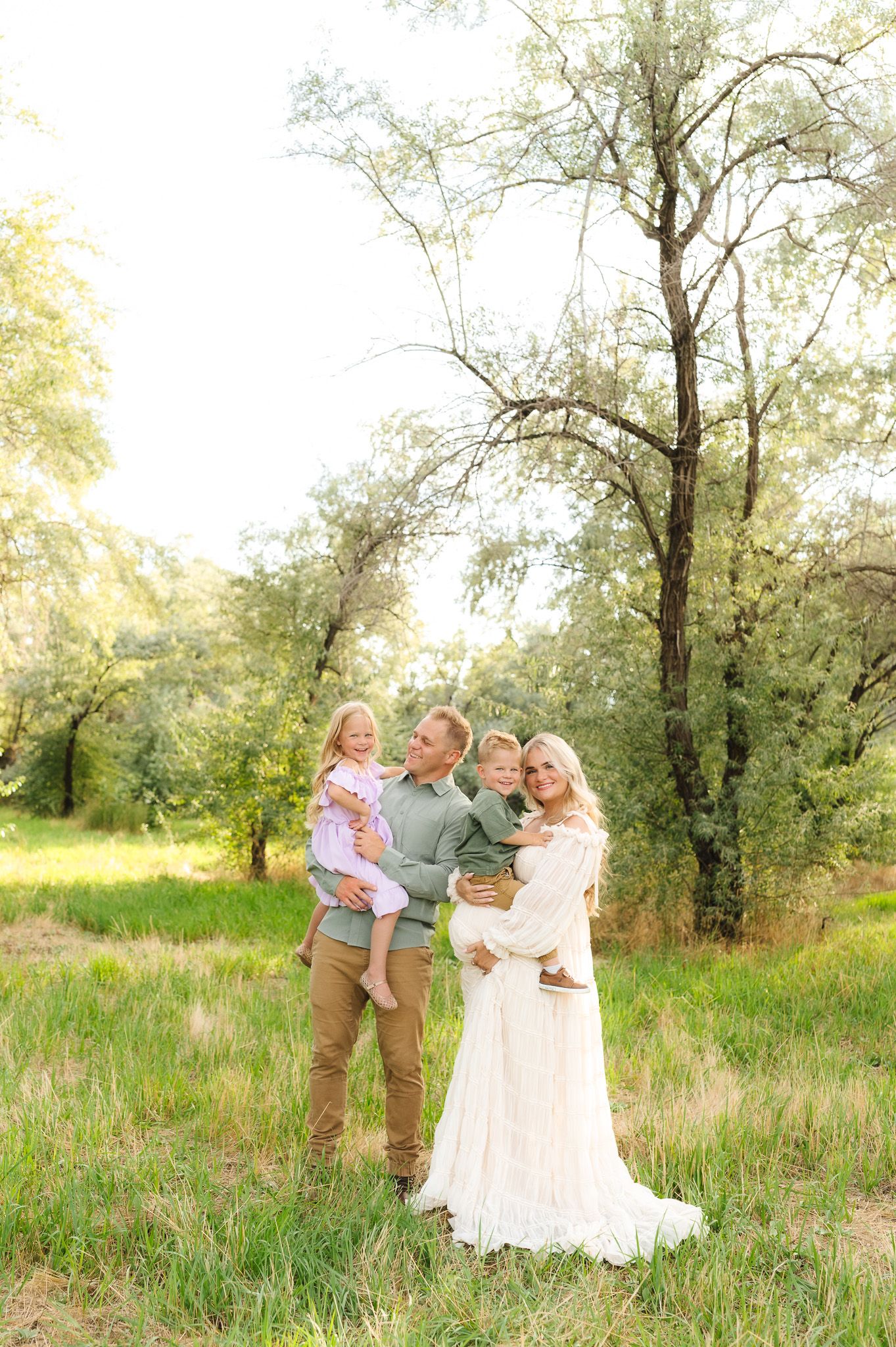 Family lifestyle session in a meadow with soft lighting and natural poses.